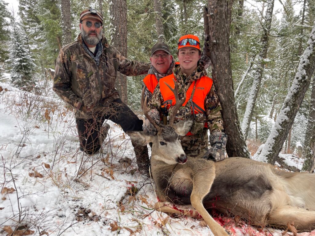 Outfitter, father, son and mule deer buck